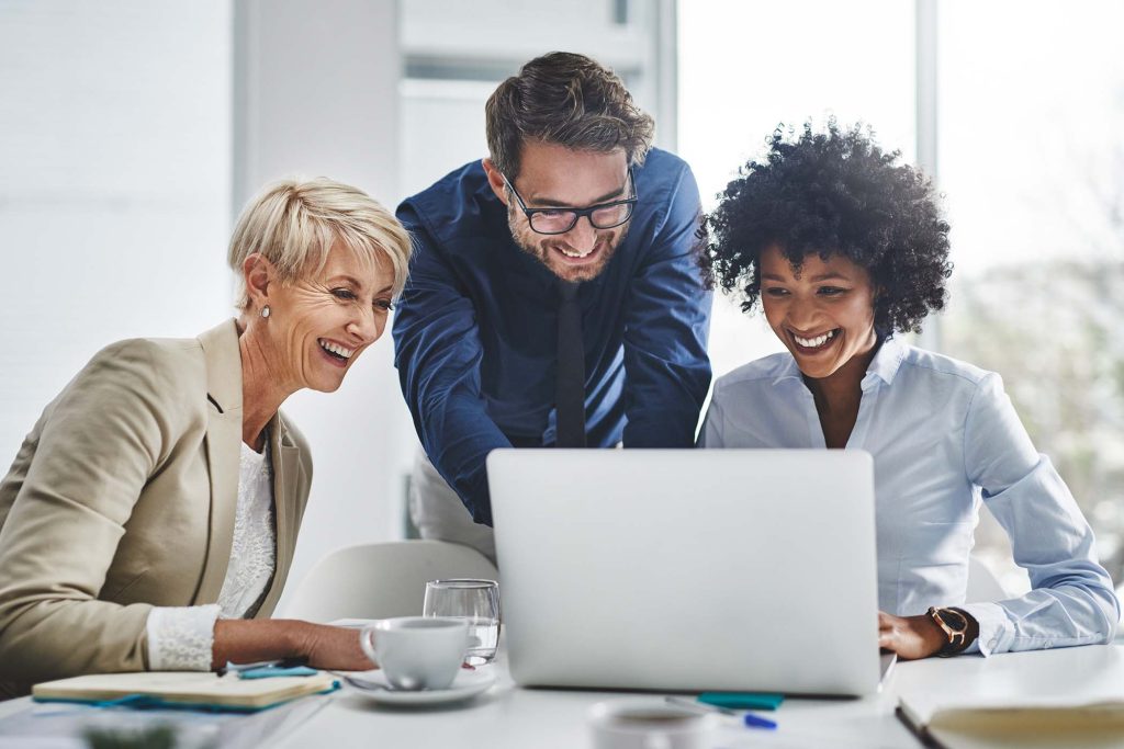 Coworkers discussing IT and Copilot while using laptop